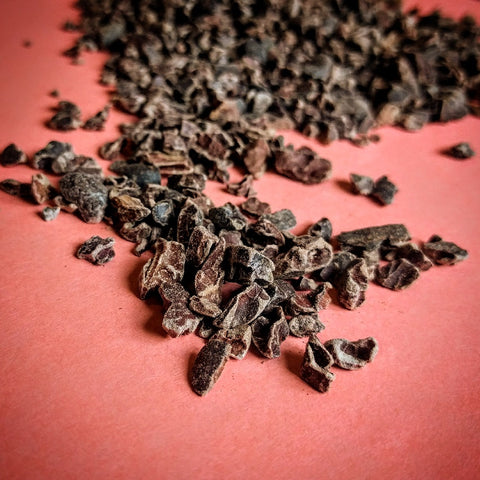 spilled cacao nibs on red background